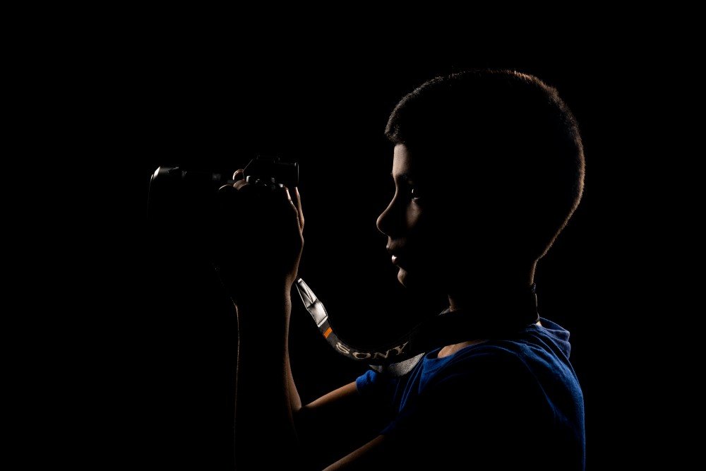 boy hold a camera and foccusing in it