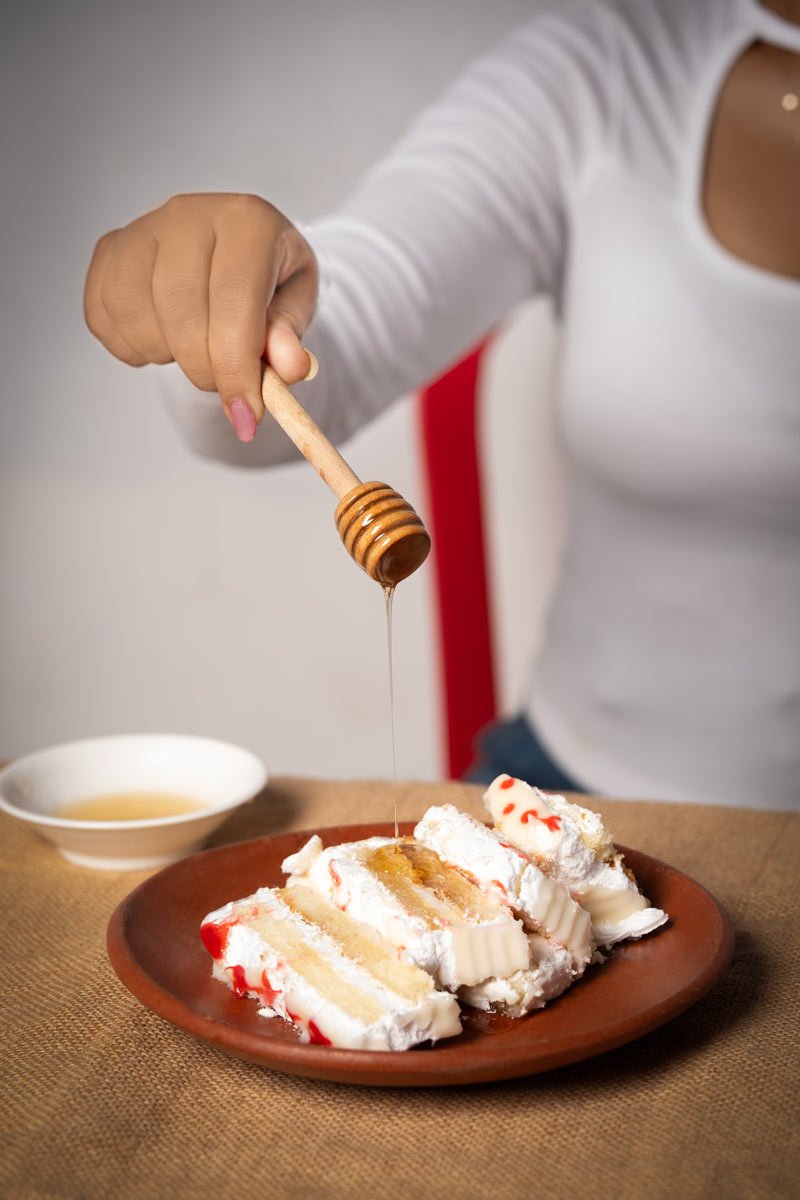 a girl dripping honey on a cake
