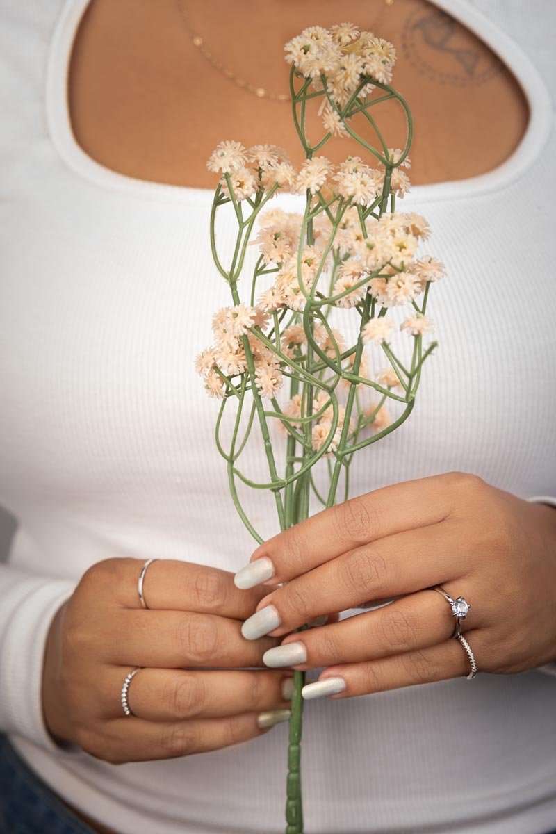 a girl is holding flowers and showcasing her rings.