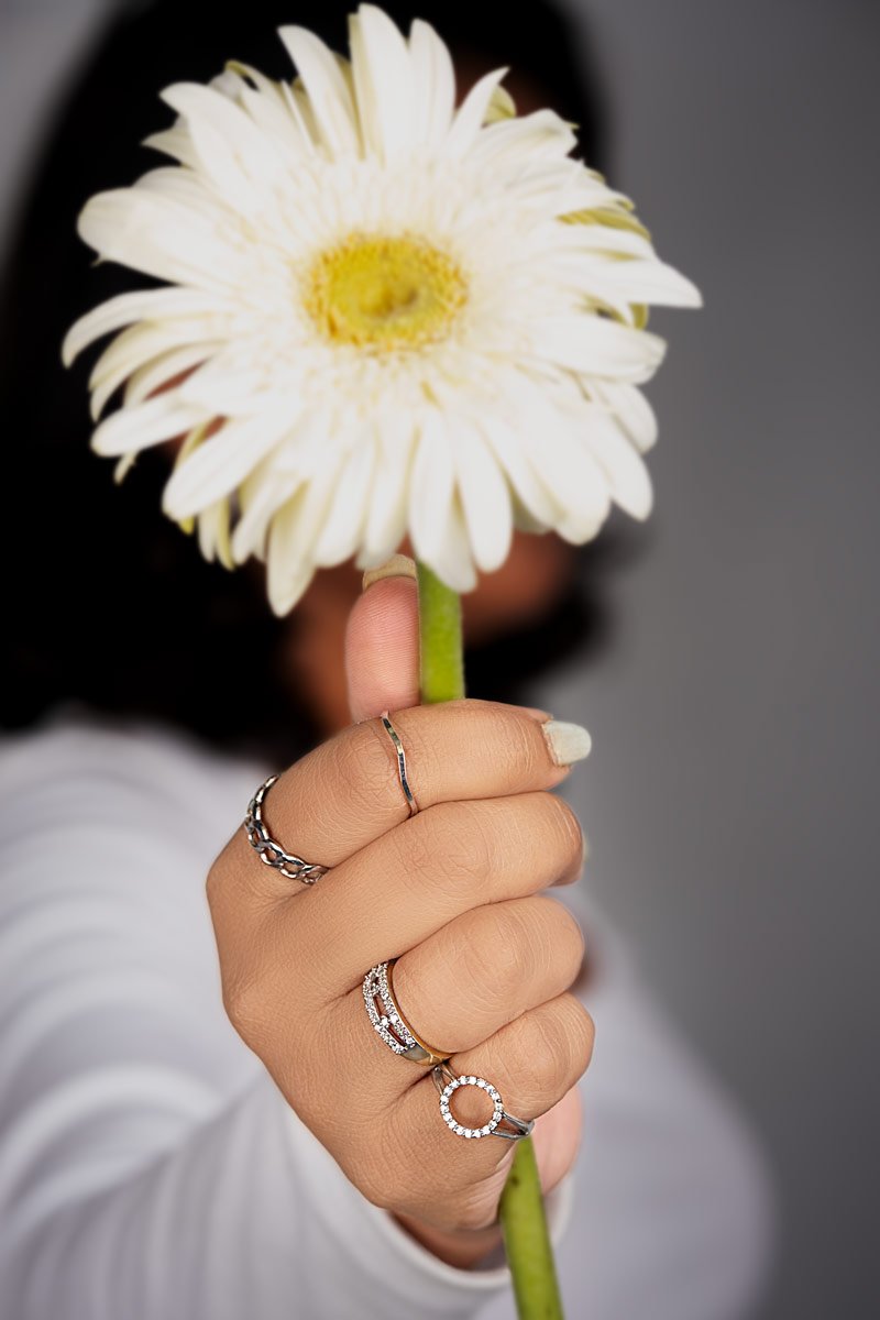 a girl is holding a flower and showcases her ring