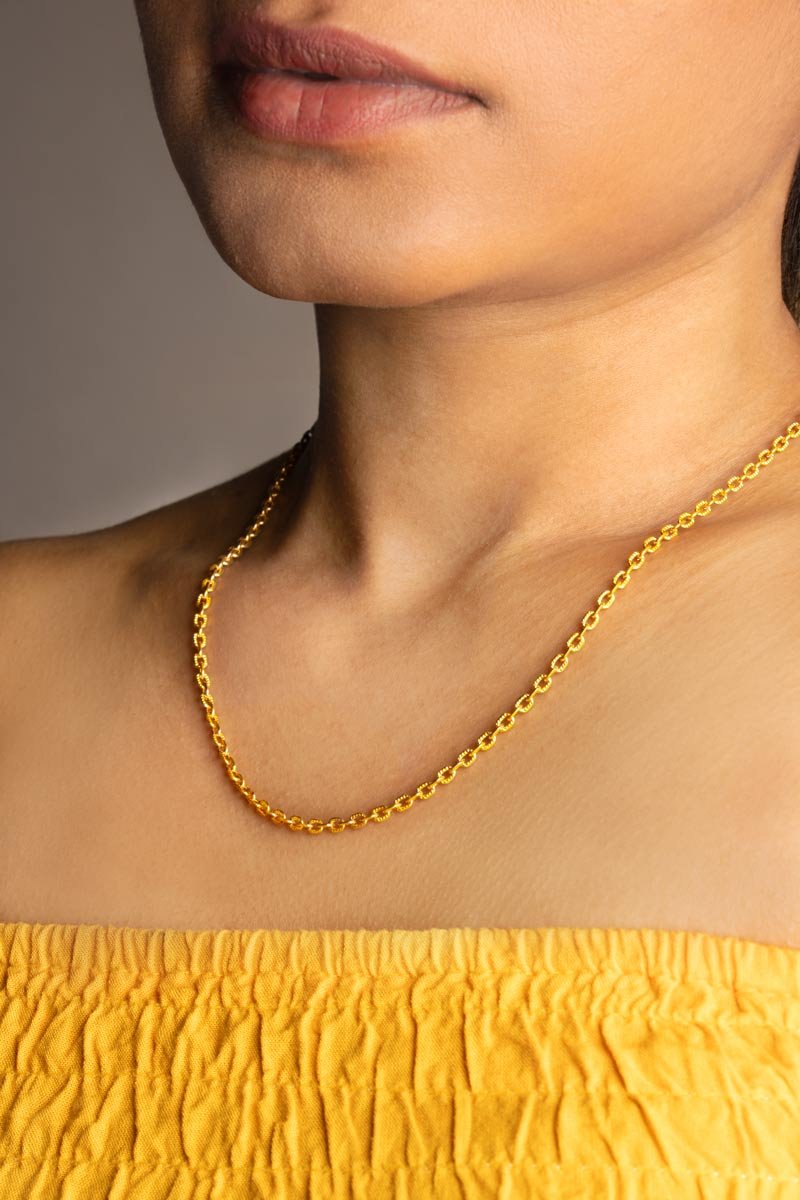 a girl is wearing a gold necklace