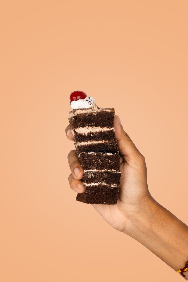 chocolate pastry with red cherry in hand