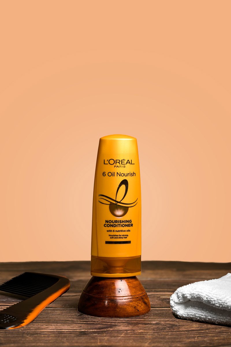 yellow conditioner bottle with comb and white towel