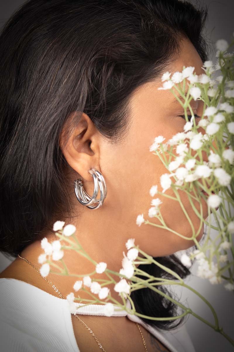 a girl is holding flowers near her face and showing her earrings
