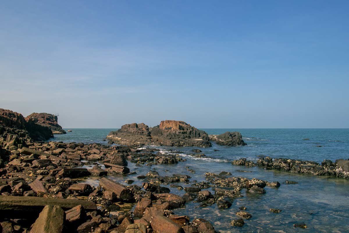 The beach has broken rock by its shore.