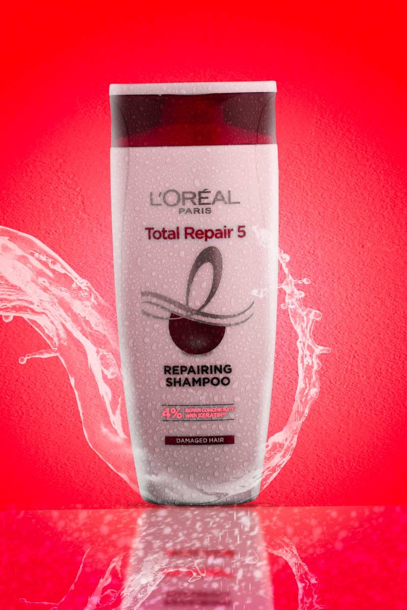 loreal paris total repair 5 shampoo with water splash in red background