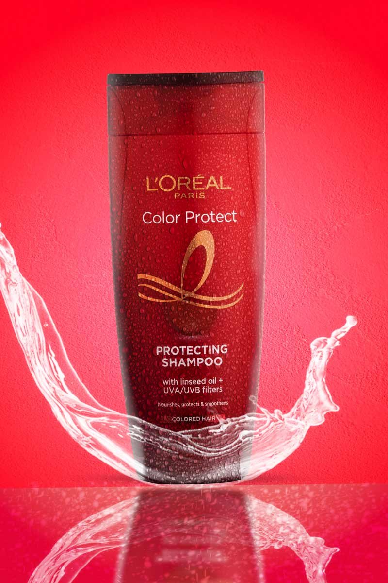 loreal paris color protect shampoo with water splash in red background