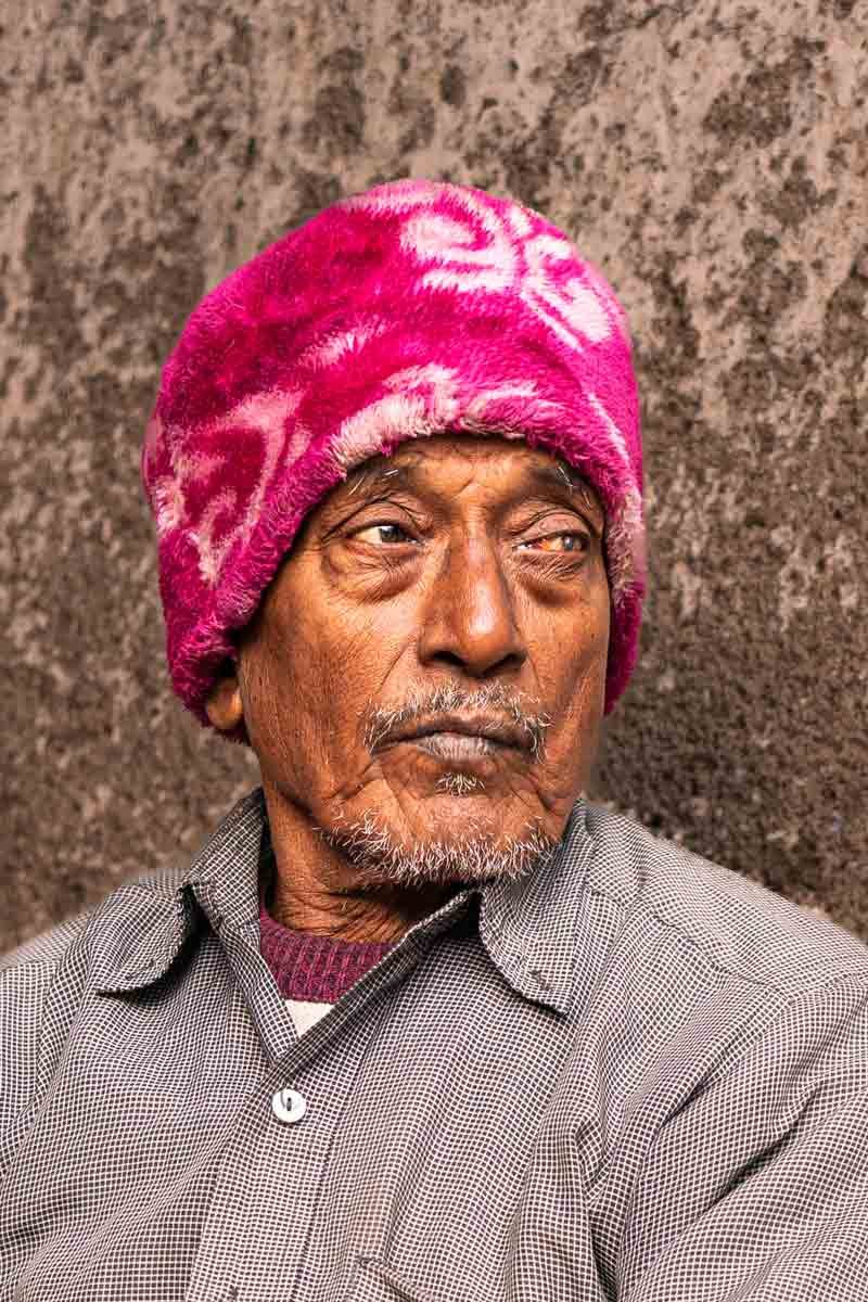 an old man wearing a pink fur cap