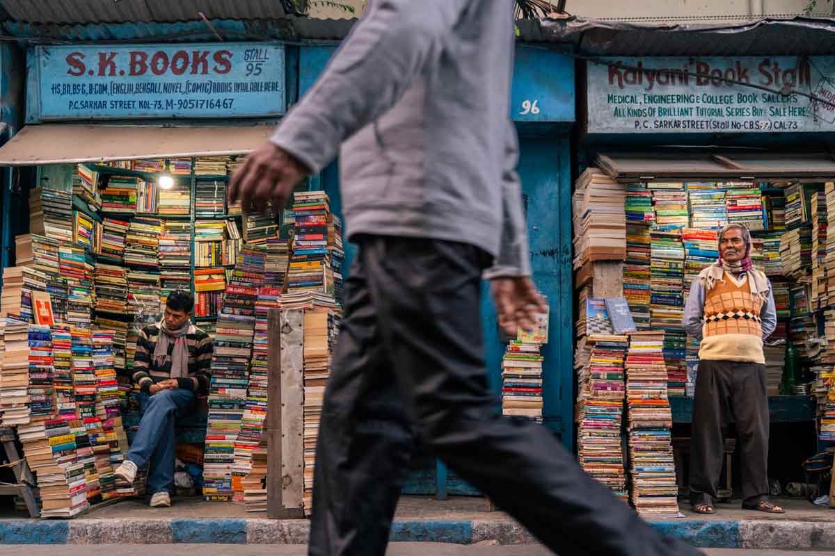 a man walking in street with book shops