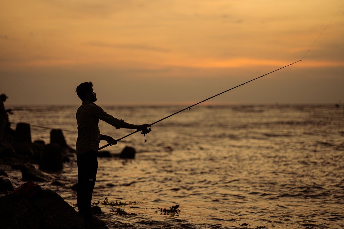 a guy is fishing in sunset time