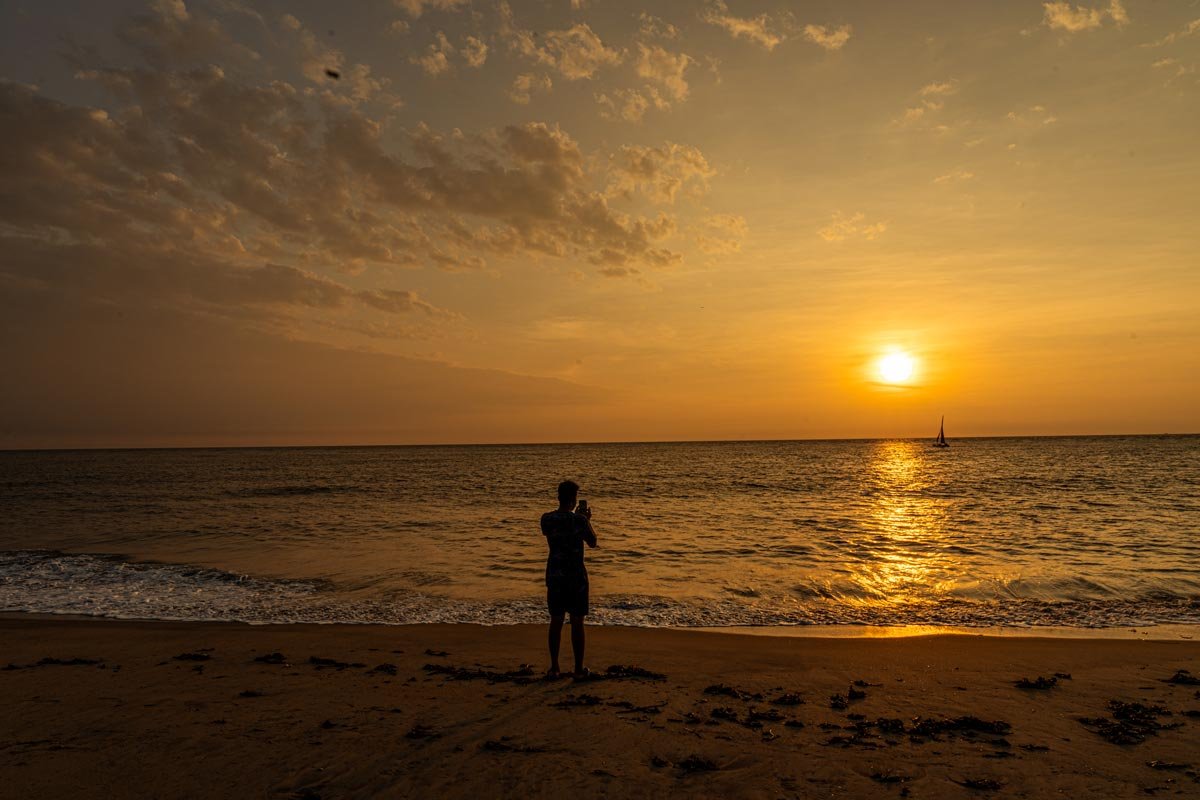 a boy is taking a picture of sunset