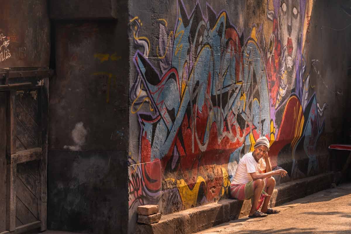 a man sitting on an empty street before graffiti