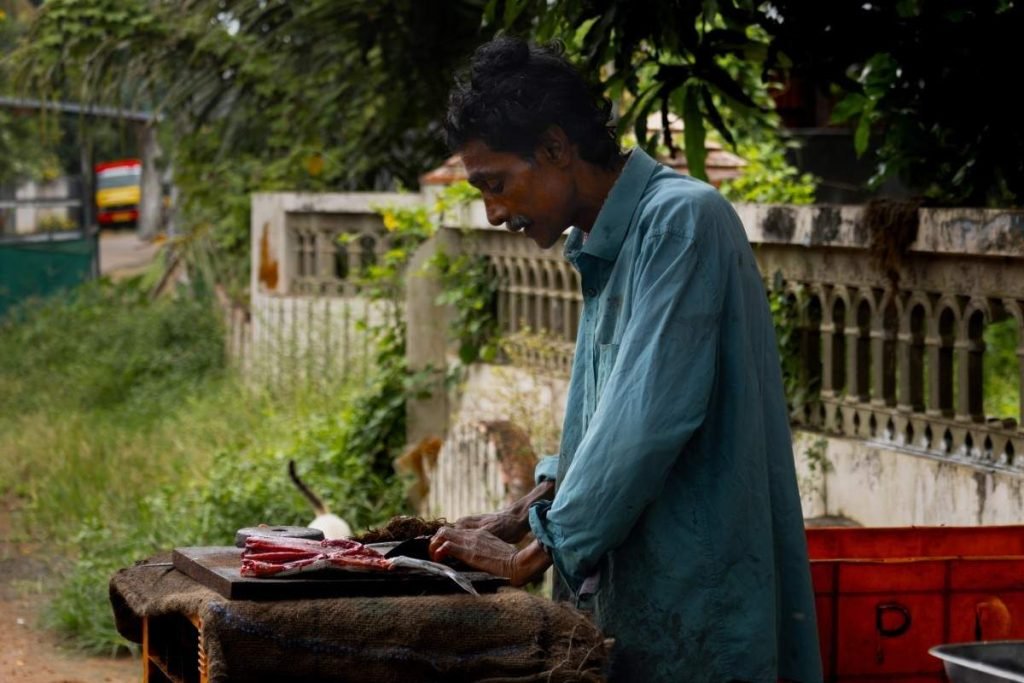 Man slicing fish with knife.