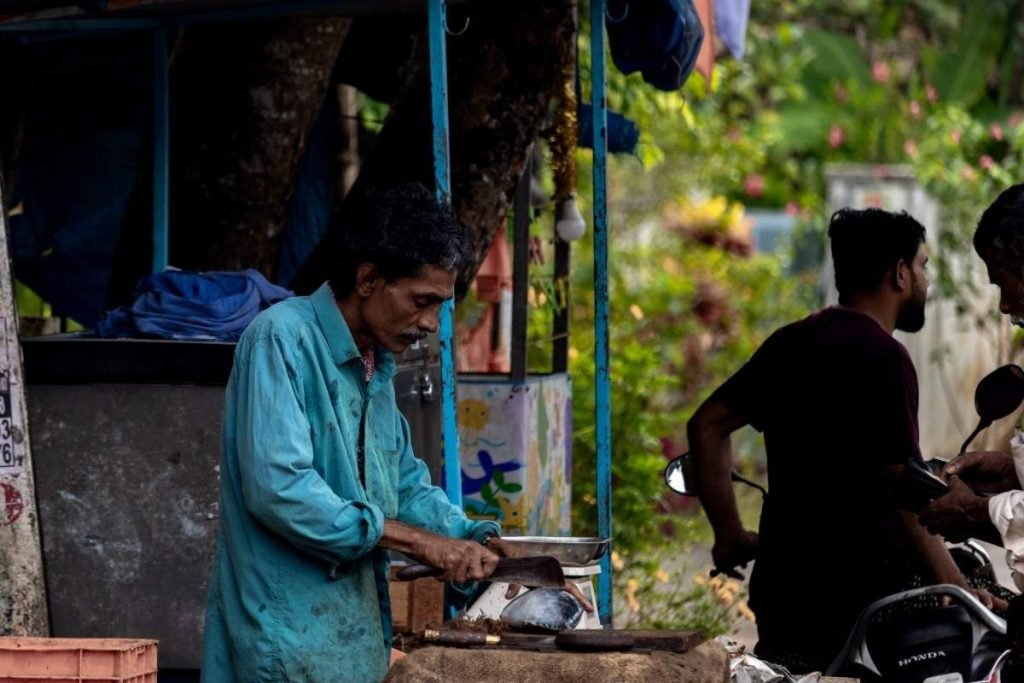 Fisherman cutting fish on street.