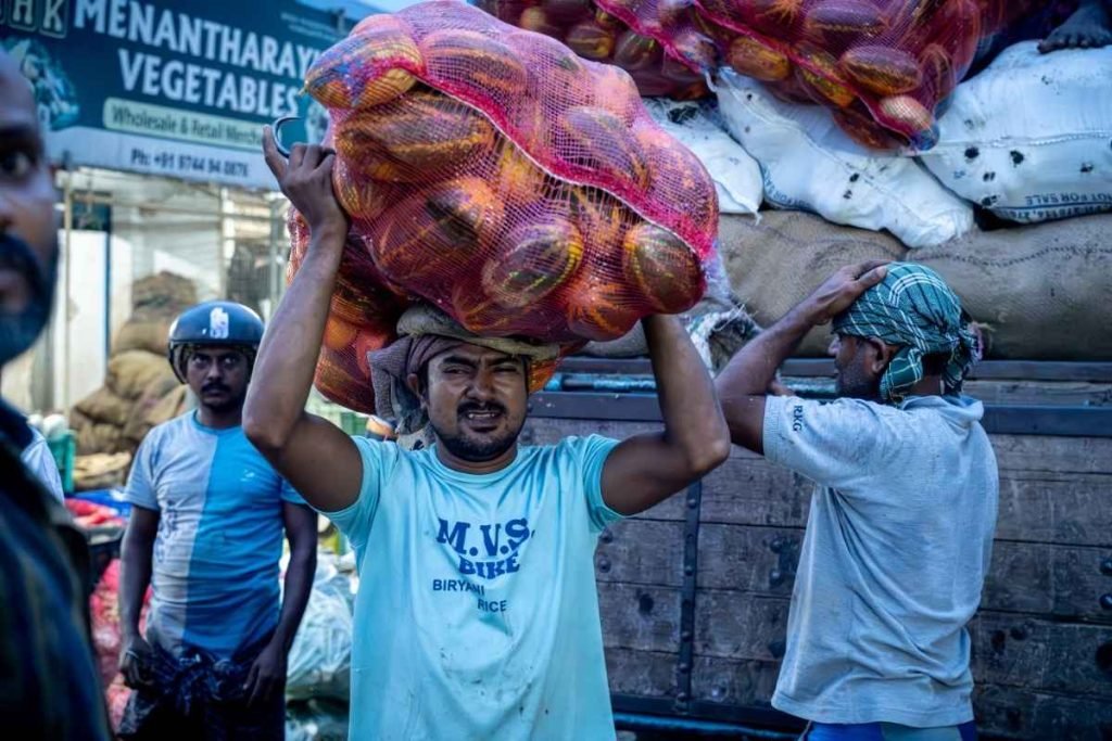 A man carrying a sack of yellow cucumbers.