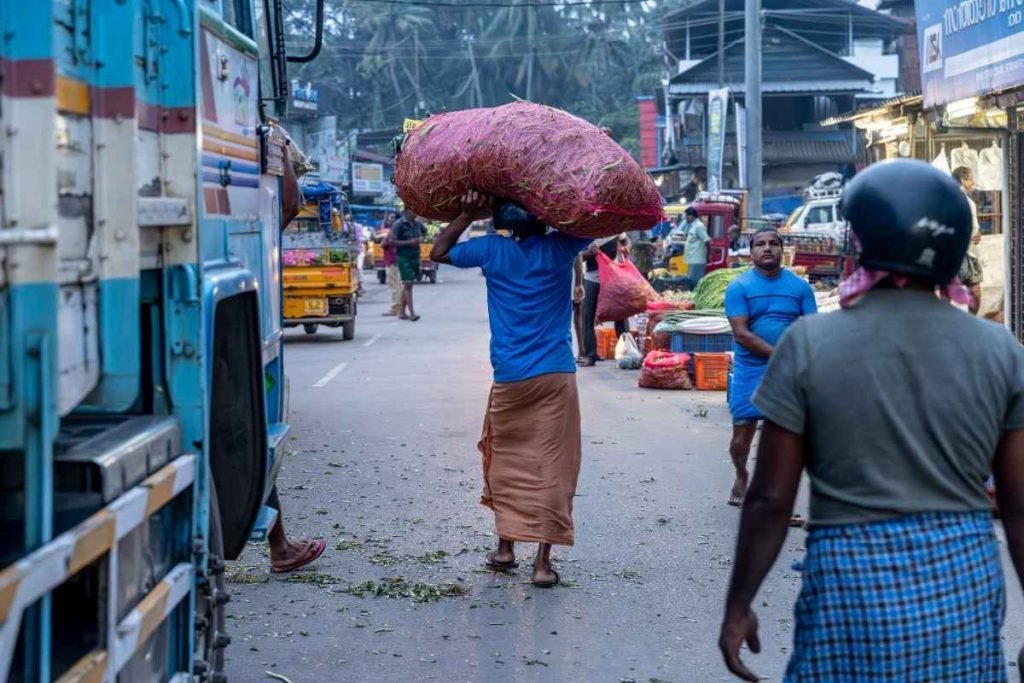 A man walking steadily while carrying heavy loads.