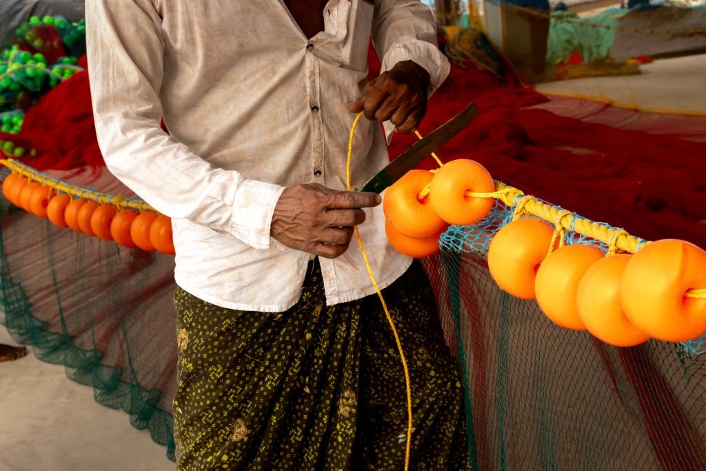 A workers hand cutting the ropes of net