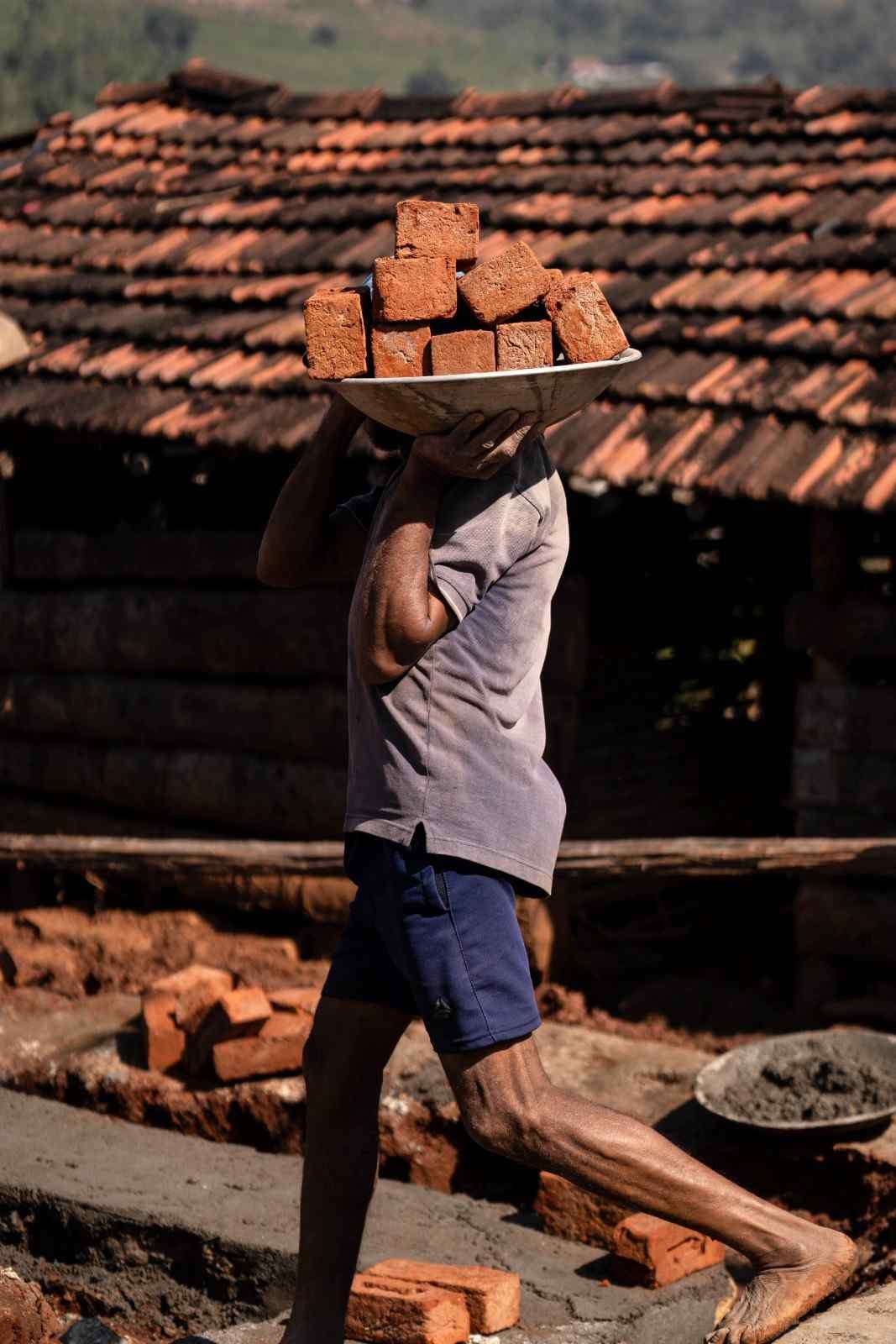 a man is carrying red bricks
