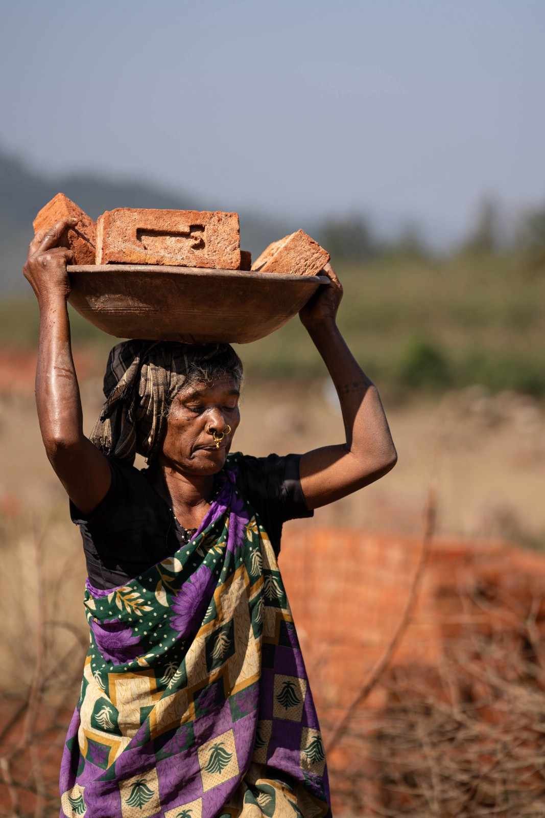 a old lady is carrying red bricks