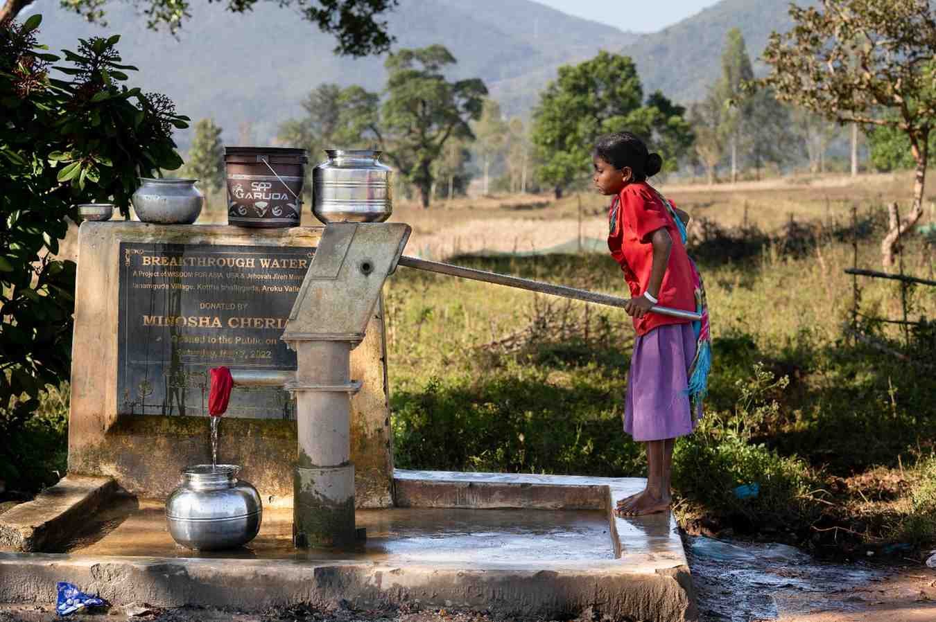 a small girl is pumping a water