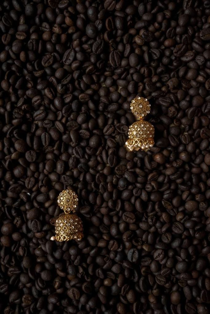 Gold jhumkas on coffee beans.