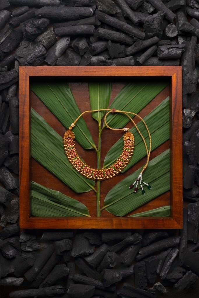 A golden necklace on a leaf surrounded by charcoal.