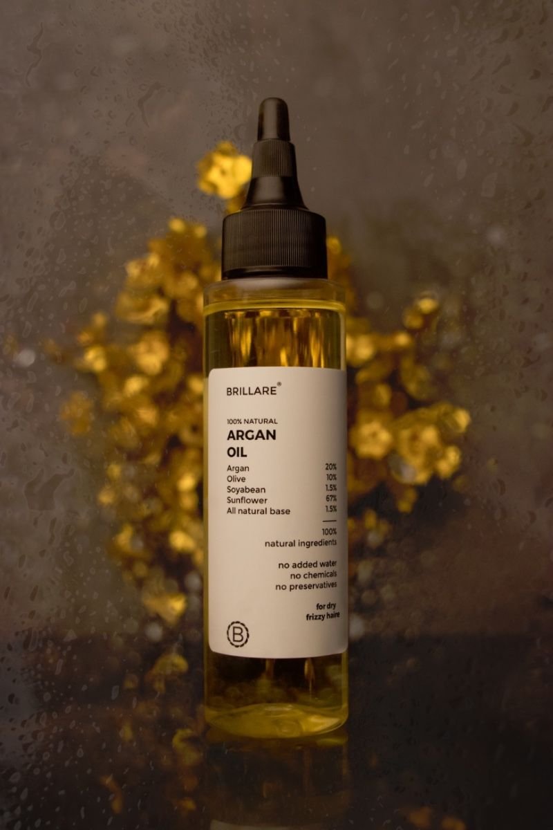 Argan oil with golden essence flowers in background