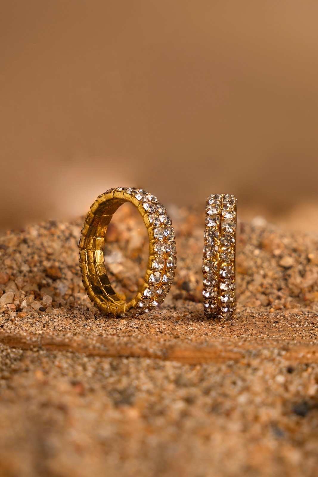 A golden diamond couple rings placed in the sand 