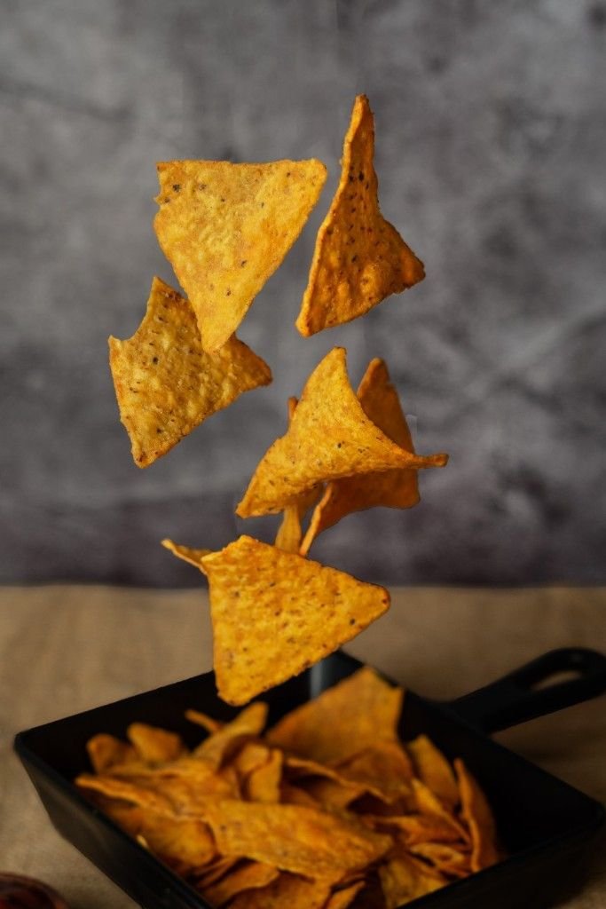 Nacho chips dropping on a plate.