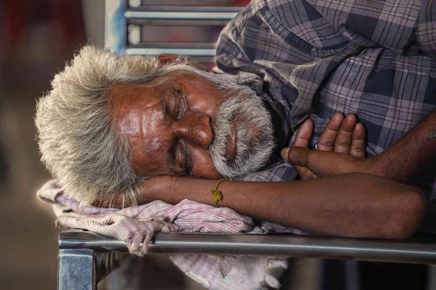 Old man resting at bus stop.