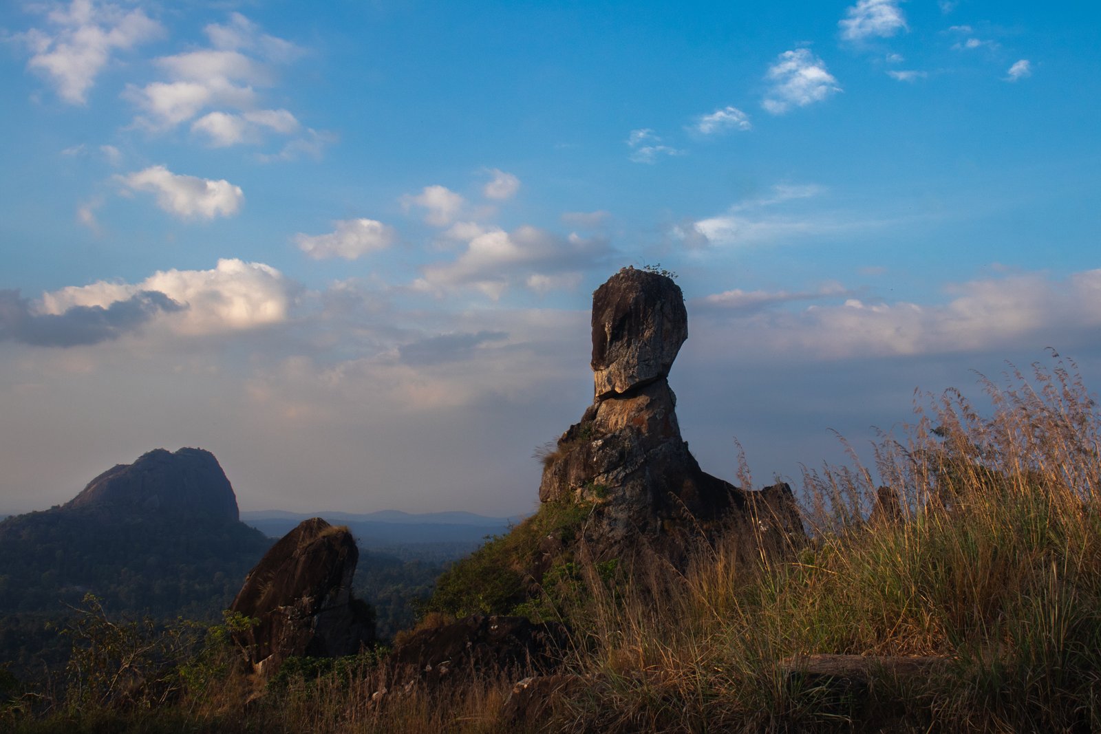 Lone rock standing high in the vast blue sky.