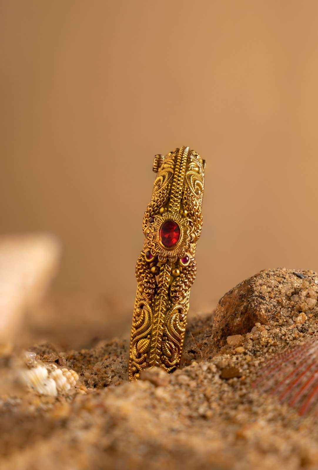 A golden bangles placed in the sand 