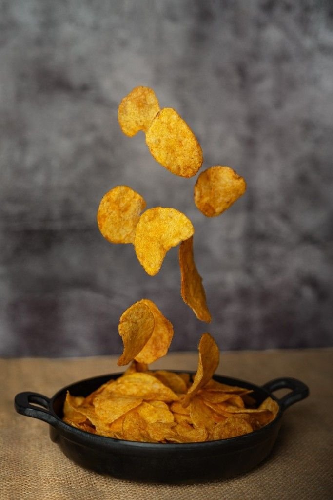 Potato chips dropping on a plate.