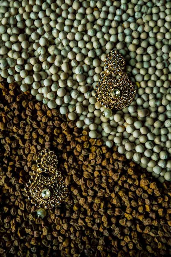 Gold earrings placed on lentils.