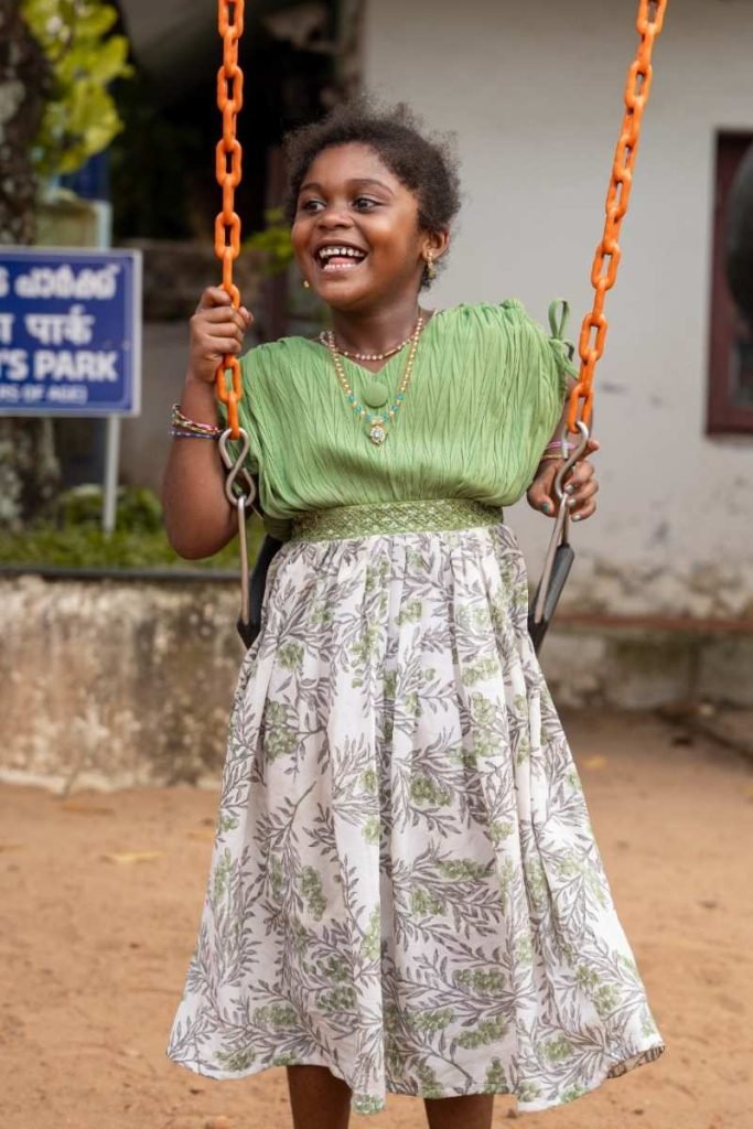 Bliss A smiling girl in a green dress swings.