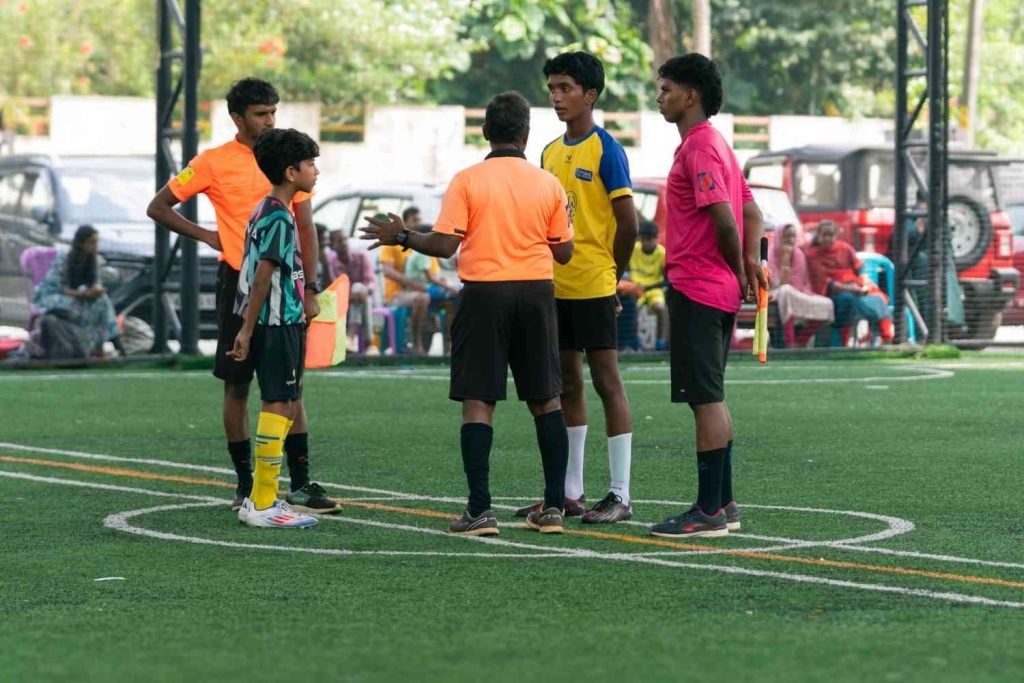 Referee instructing two football captains on match regulations before kickoff.