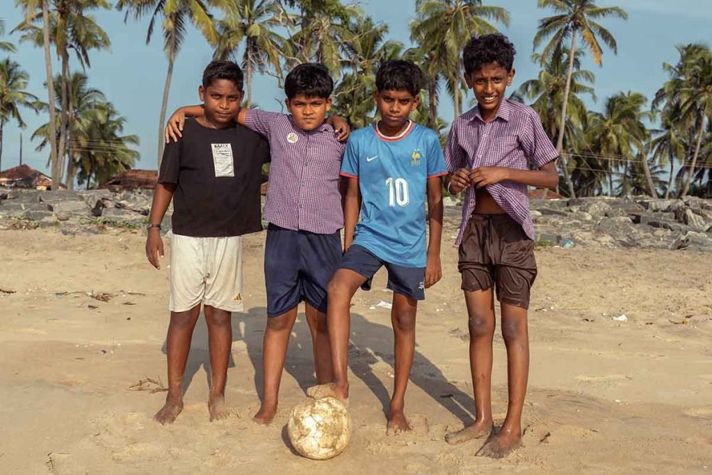 A group of boys posing for the camera with a football showing their passion.