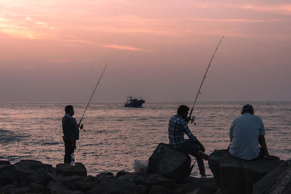 Patience As the sun dips below the horizon, fishermen wait in quiet anticipation with their lines cast into the sea.