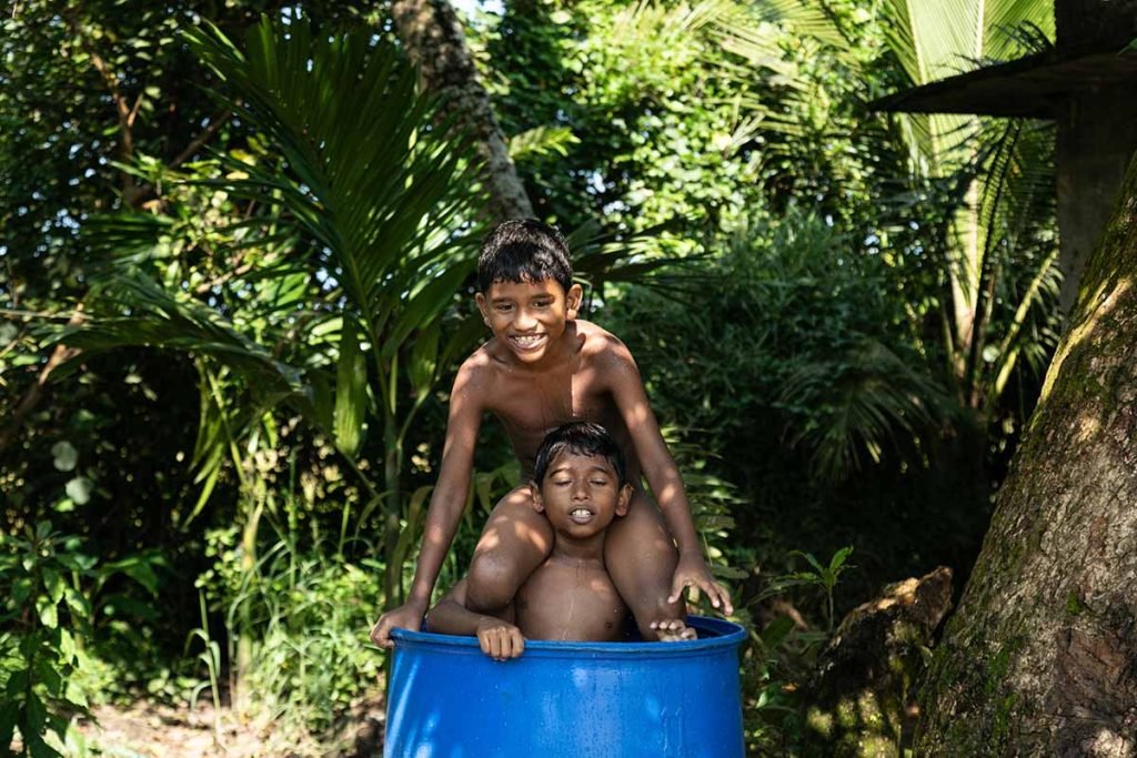 Playful Chaos Two kids laugh and play in a barrel.