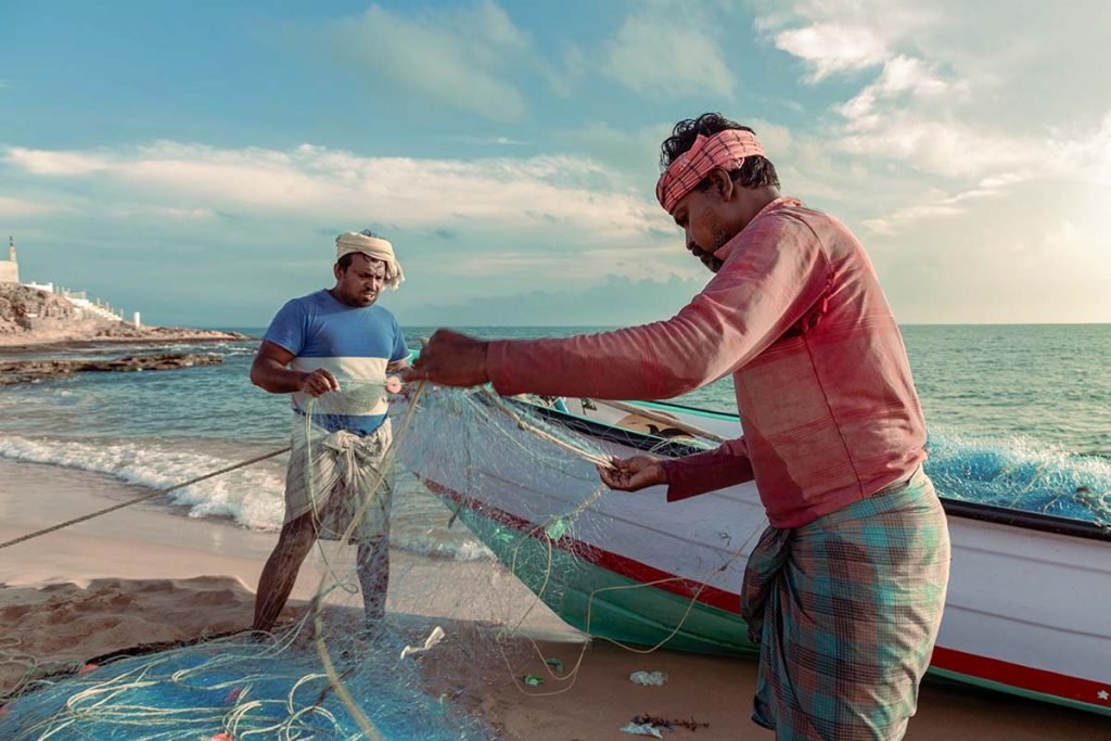 shoreline hustle between two fishermen mending nets.